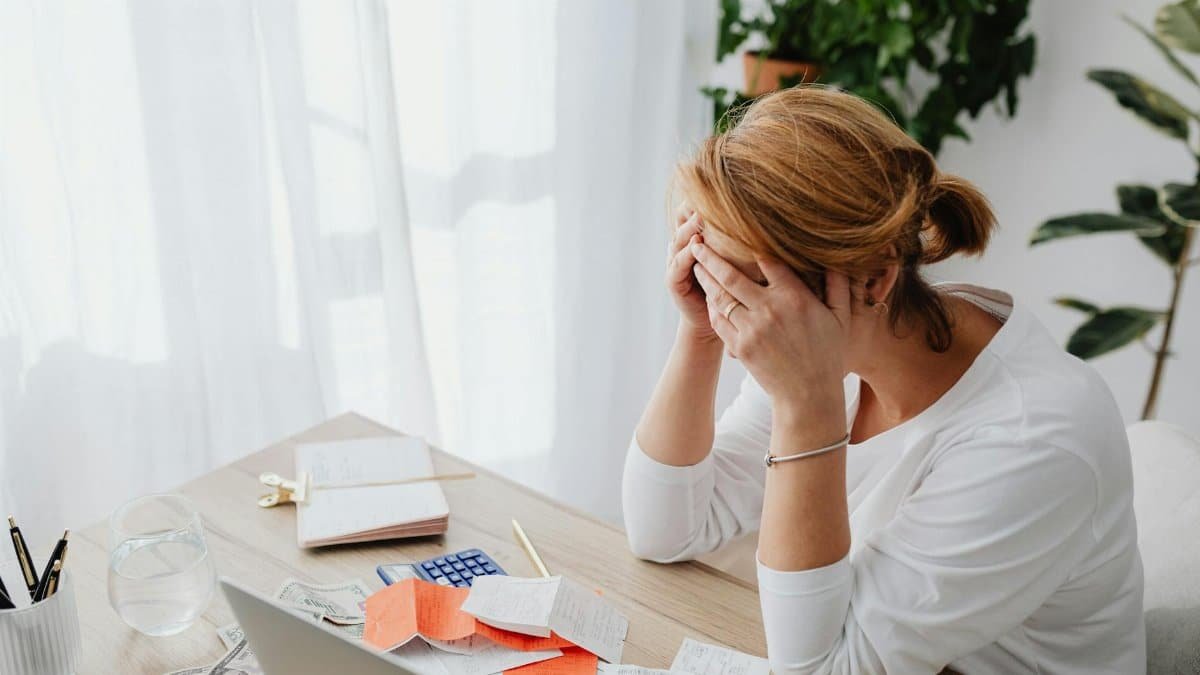 Woman stressed over financial receipts at a desk, dealing with expenses and calculations.