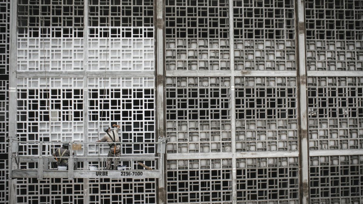 High-rise workers on suspended platform in São Paulo, Brazil, painting geometric facade.