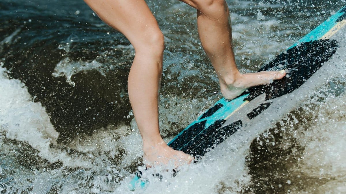 Close-up of a surfer skillfully balancing on a surfboard amidst splashing ocean waves.