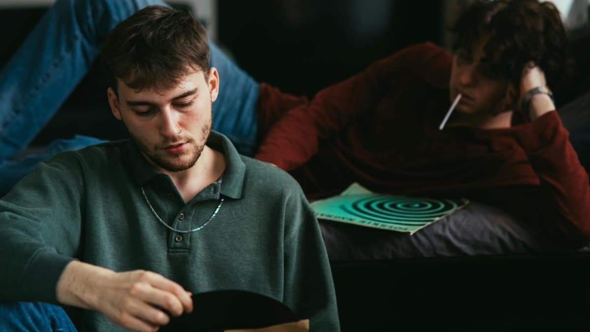 Two young men enjoying vinyl records in a laid-back indoor setting.