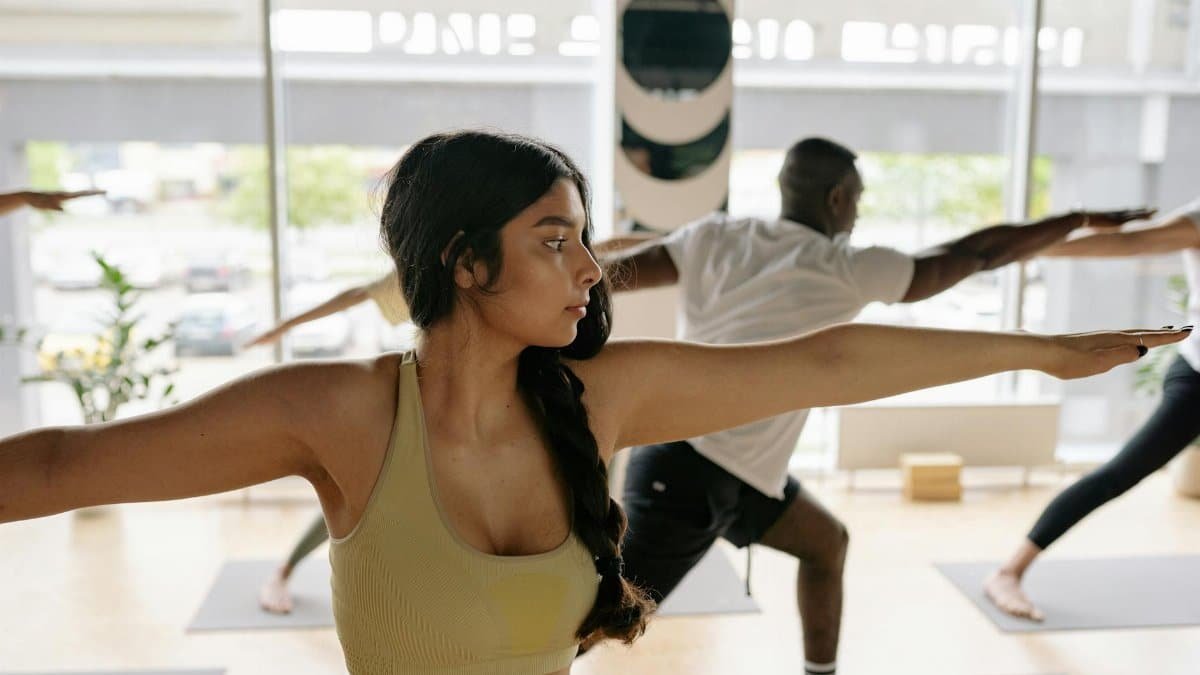 Diverse group practicing yoga warrior pose indoors for fitness and wellness.