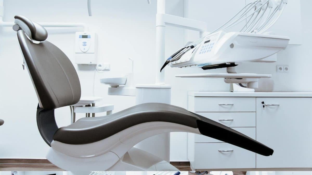 A modern dental clinic interior showcasing a dental chair and equipment in a clean, clinical setting.