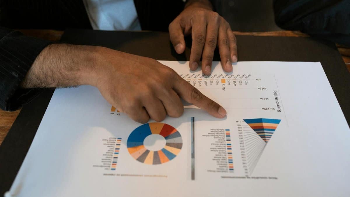 Hands pointing at colorful graphs and charts in a workspace. Ideal for business presentations and reports.