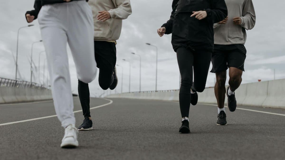 Four people jogging together on an urban road, showcasing fitness and teamwork.
