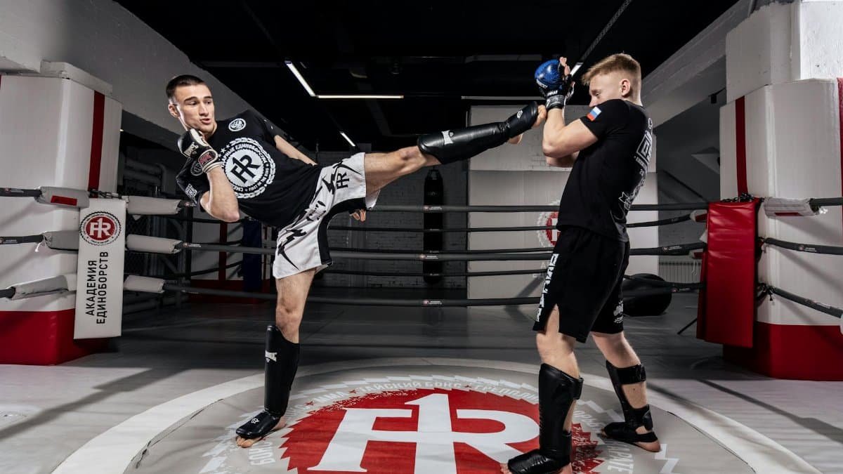Two men in action-packed kickboxing training in sportswear inside a ring.