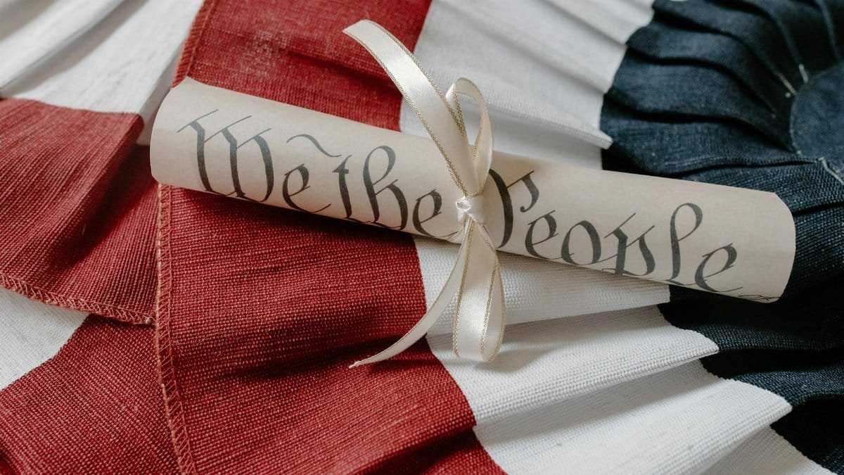 Close-up of a 'We the People' scroll on an American flag cloth background.
