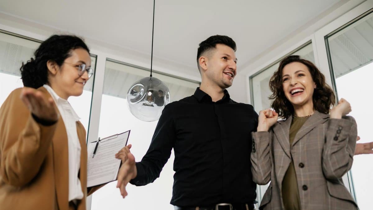 A joyful couple and their realtor celebrate successfully buying a new house indoors.