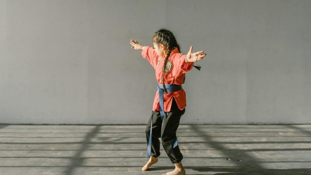 A young martial artist in uniform practicing indoors with focus and energy.