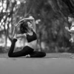 Black and white photo of a woman practicing yoga with a child in a peaceful outdoor setting.