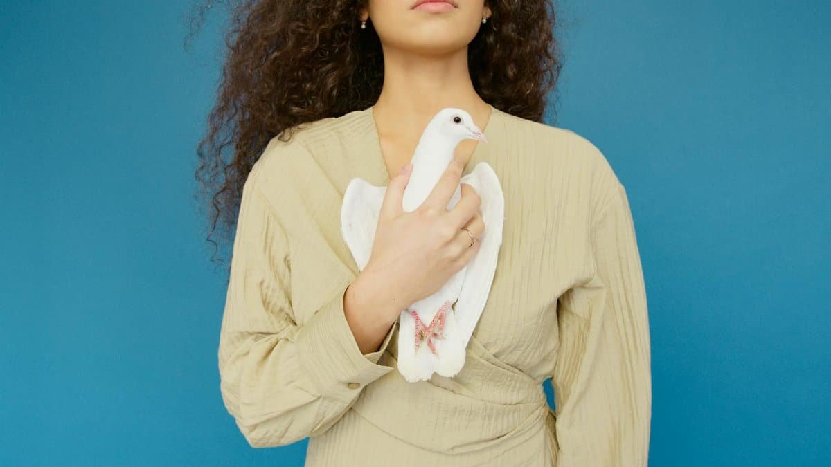 Close-up portrait of a woman holding a white dove, symbolizing peace and purity.