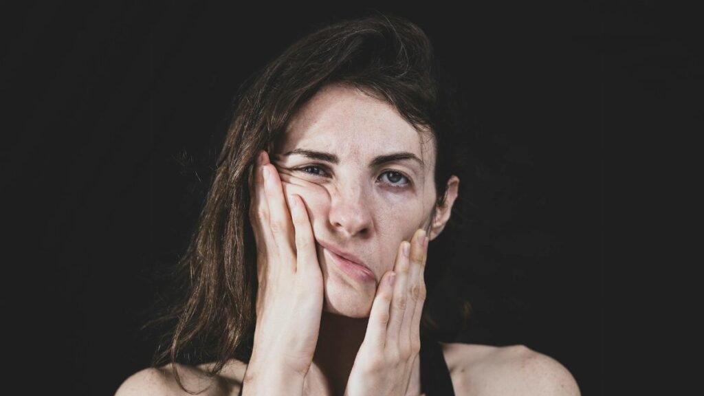 Close-up of a woman massaging her face, reflecting stress and anxiety.