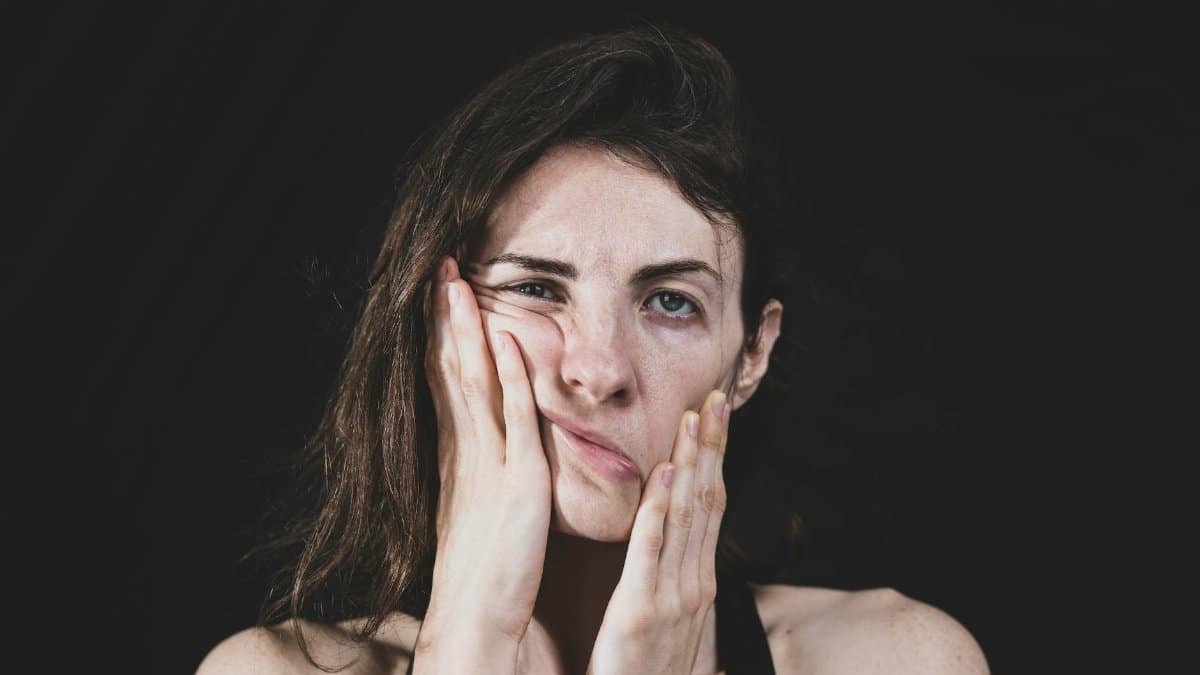 Close-up of a woman massaging her face, reflecting stress and anxiety.