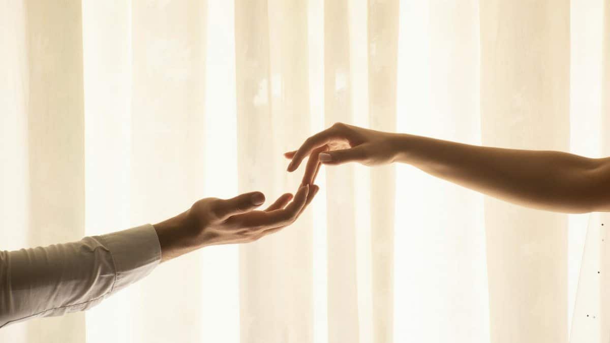 Two hands reaching out to each other in soft, warm lighting.