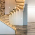 Contemporary hall interior with door against curved staircase and wall with geometric ornament in light house