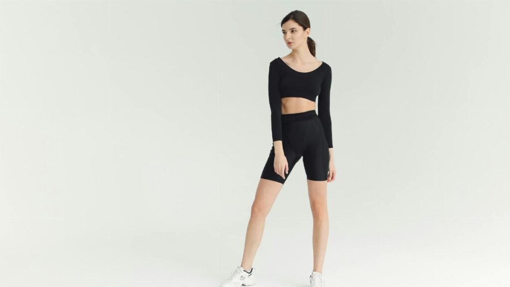 A sporty young woman poses confidently in stylish fitness attire, showcasing a modern activewear look.