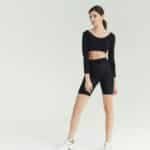A sporty young woman poses confidently in stylish fitness attire, showcasing a modern activewear look.