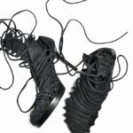 Pair of stylish black lace-up high-heeled boots on a white background showcasing intricate laces.