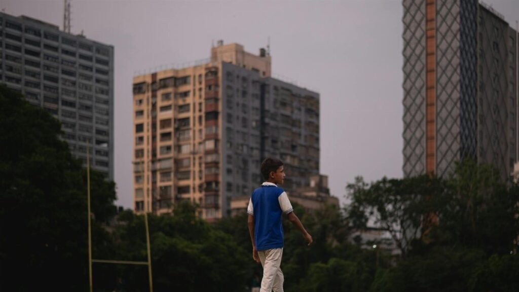 A child strolls through a city park surrounded by high rise buildings during dusk, capturing urban tranquility.