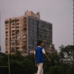 A child strolls through a city park surrounded by high rise buildings during dusk, capturing urban tranquility.