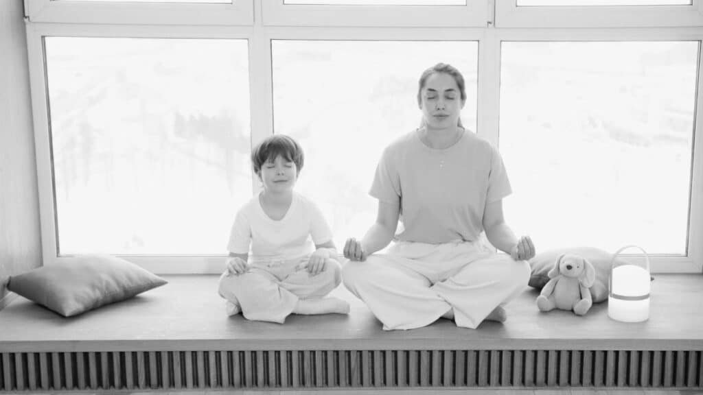 Mother and son practicing meditation, sharing a peaceful moment in a sunlit room.
