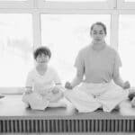 Mother and son practicing meditation, sharing a peaceful moment in a sunlit room.