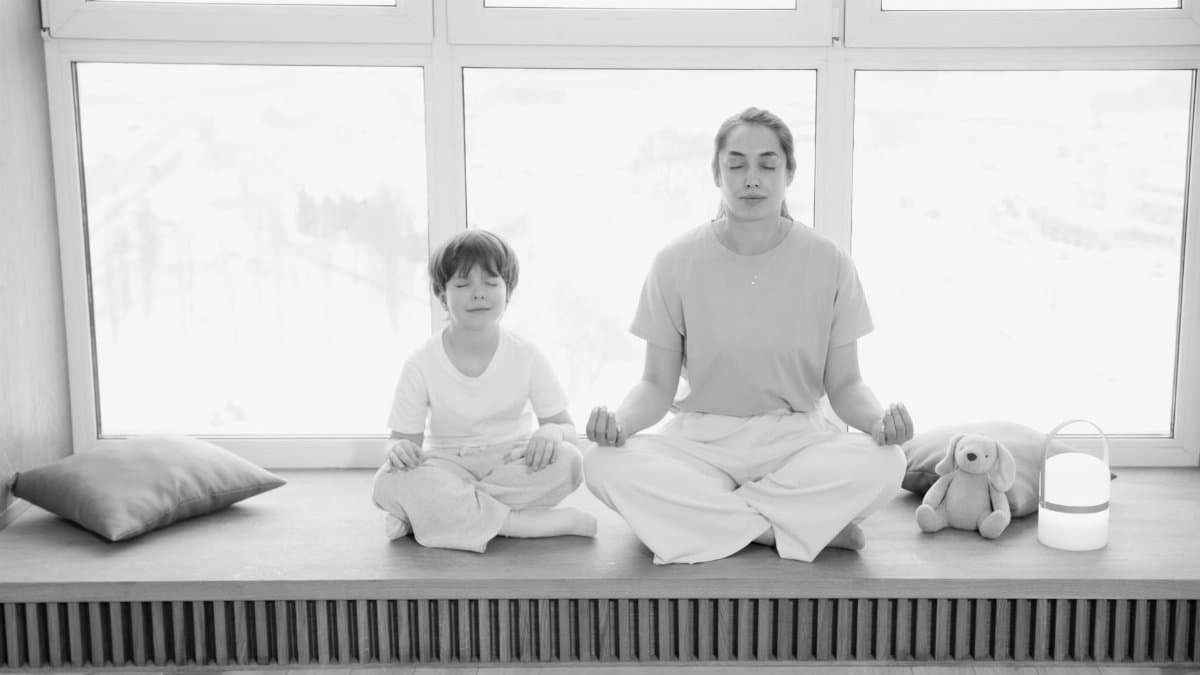 Mother and son practicing meditation, sharing a peaceful moment in a sunlit room.