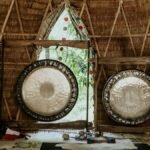 Interior view of a bamboo hut featuring traditional gongs used for sound healing and meditation.