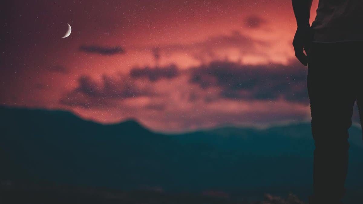 A lone silhouette against a vibrant red twilight sky in Colorado Springs.