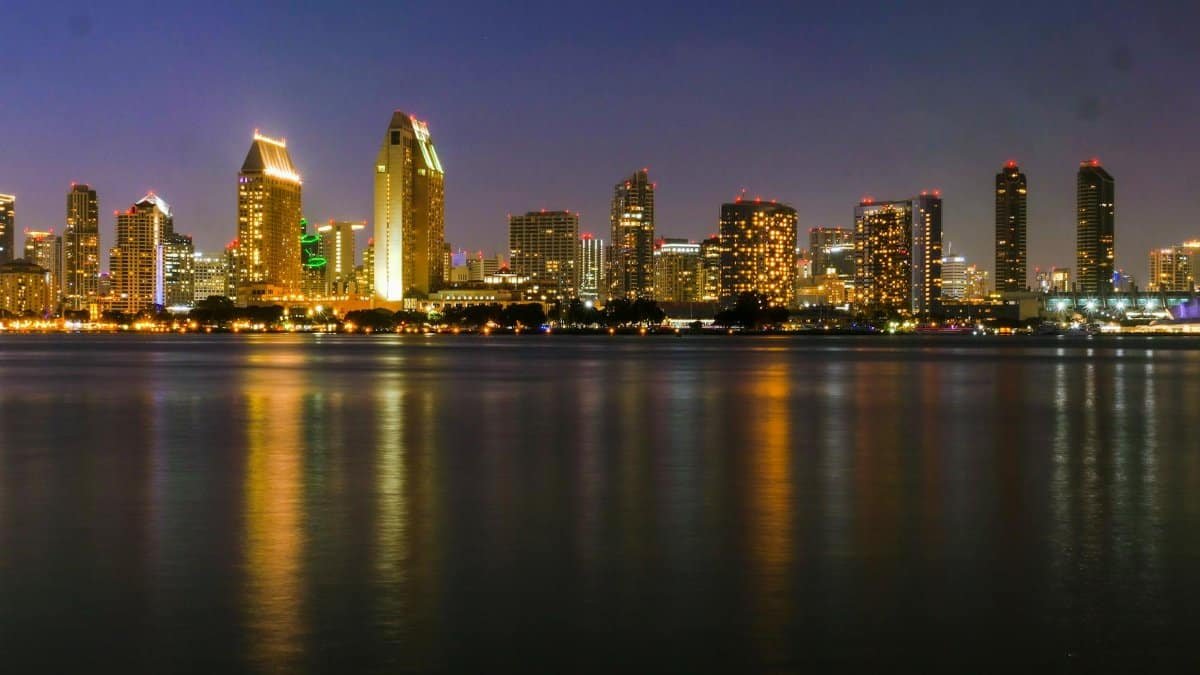 Captivating view of San Diego skyline reflecting on the water at night with city lights.