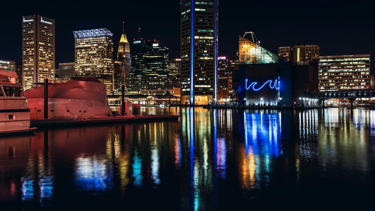 Vibrant Baltimore skyline at night with reflections on Inner Harbor water.