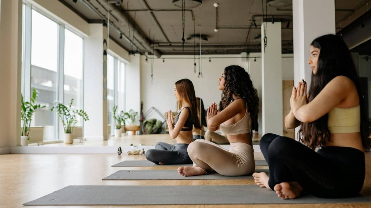 Group of women focused on meditation and yoga pose in a modern indoor studio.