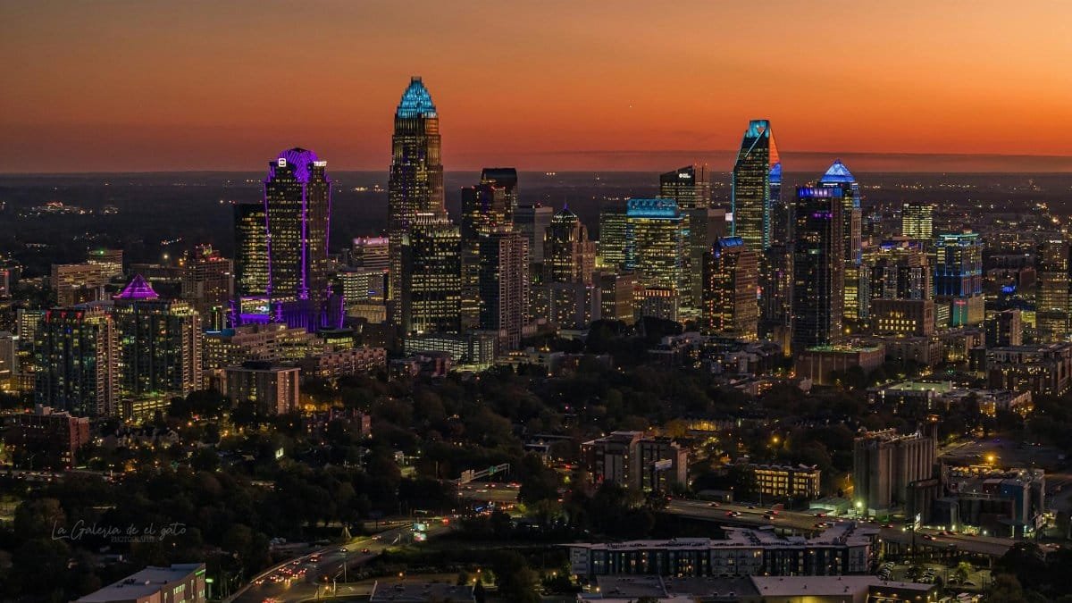 Aerial view of Charlotte cityscape with illuminated skyscrapers at twilight, showcasing urban beauty.