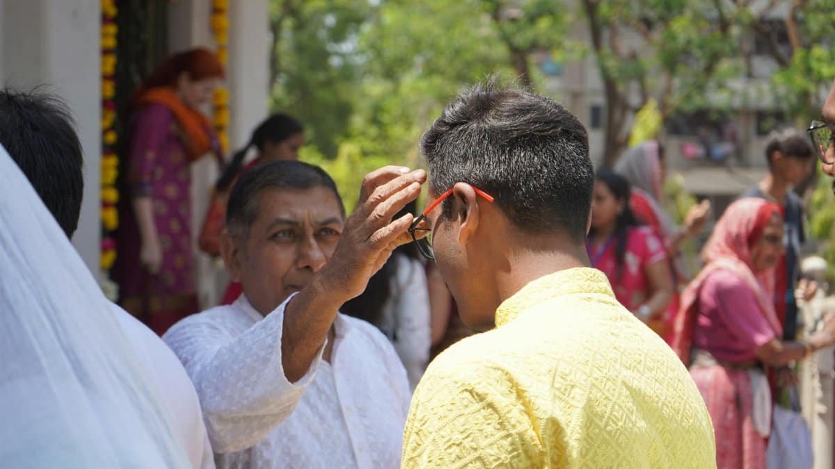 An outdoor gathering of people at a Hindu blessing ceremony, featuring spiritual rituals and cultural attire.