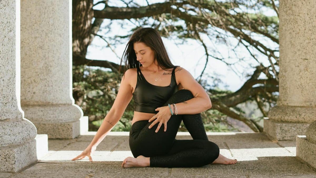 Woman practicing yoga outdoors, conveying tranquility and mindfulness amidst stone columns.