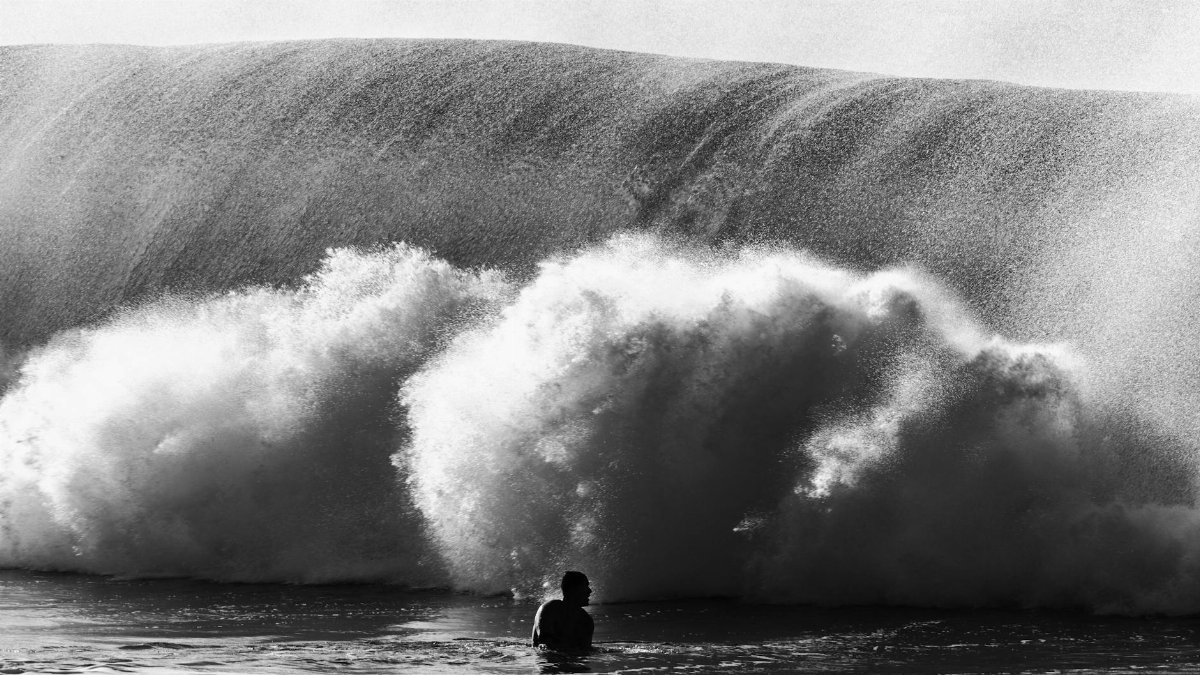 Silhouette of a person facing a large ocean wave in Hawaii, capturing the raw power of nature.