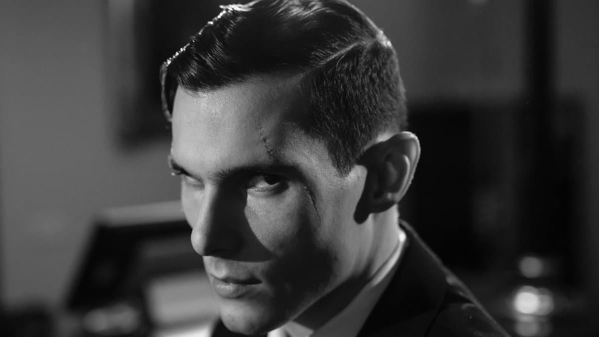 Cinematic black and white portrait of a serious man with a scar and intense expression.