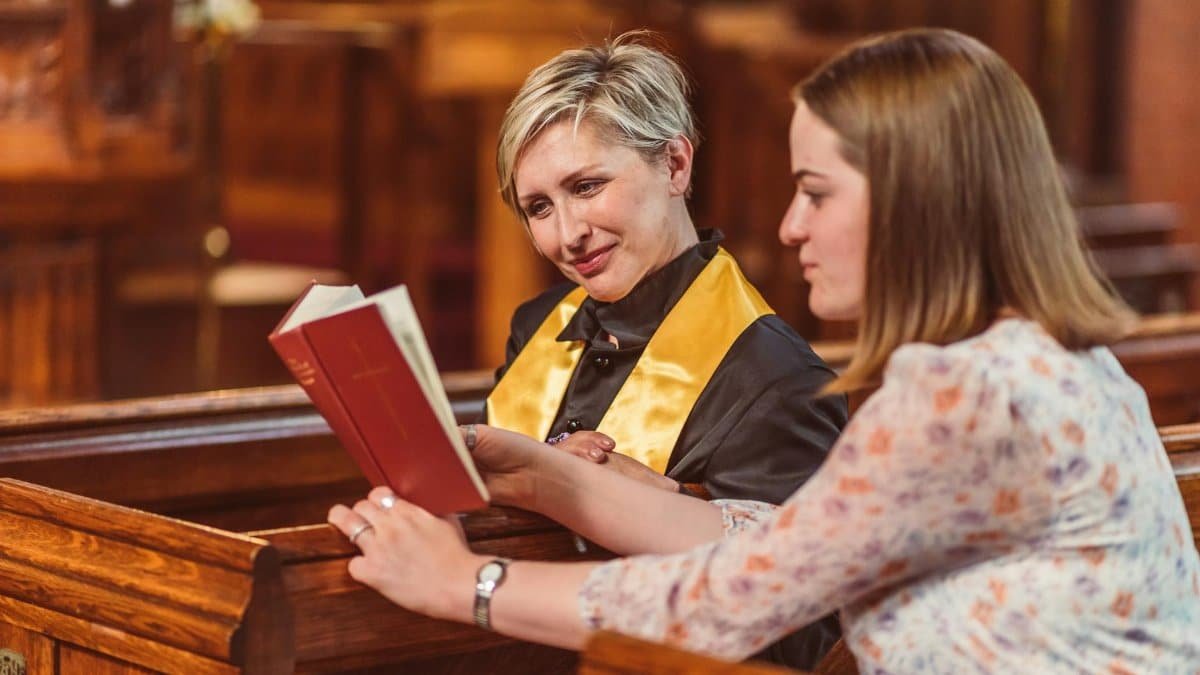 Two women in a church discussing scripture together, fostering spiritual growth and connection.