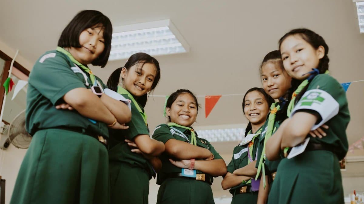 Group of girl scouts smiling confidently indoors, representing teamwork and leadership.