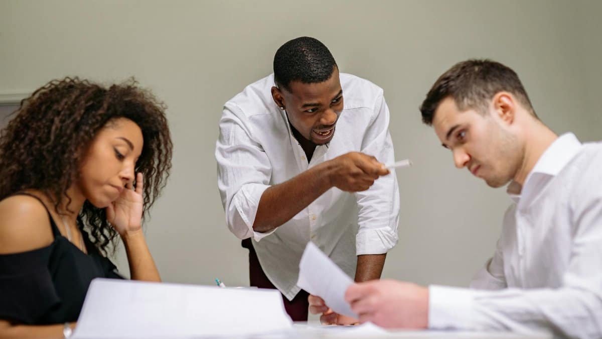 Dynamic office scene showing a tense discussion among diverse coworkers around a table.
