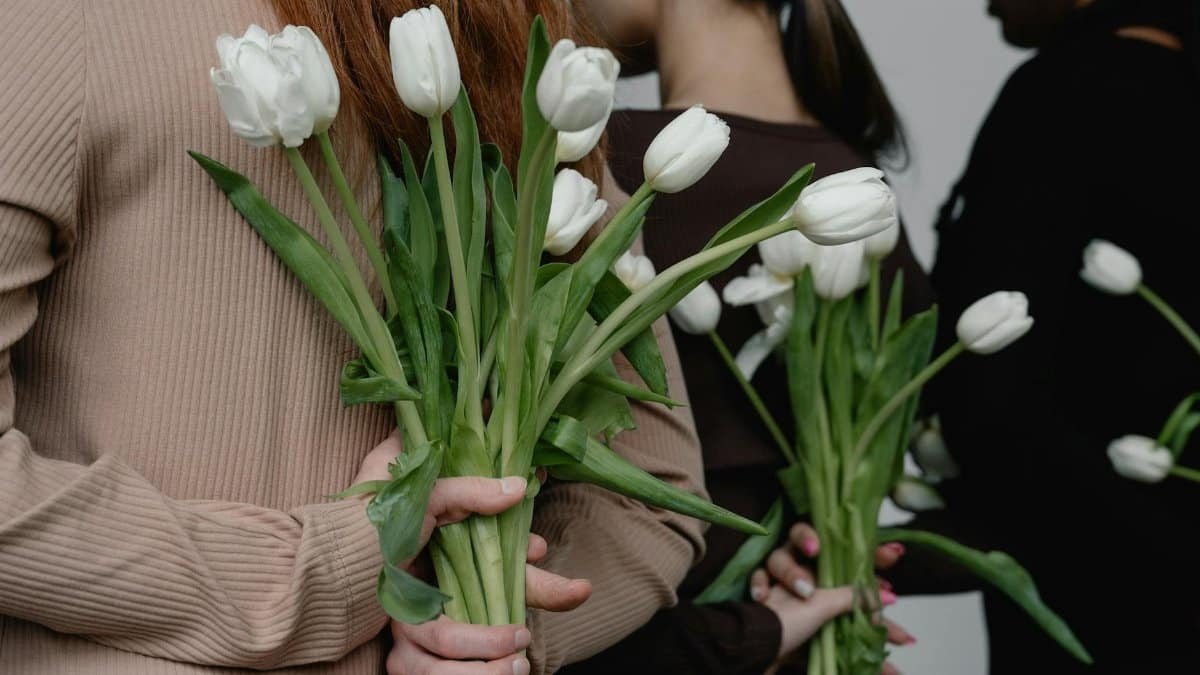 A diverse group showcasing white tulip bouquets held behind their backs, symbolizing unity and elegance.