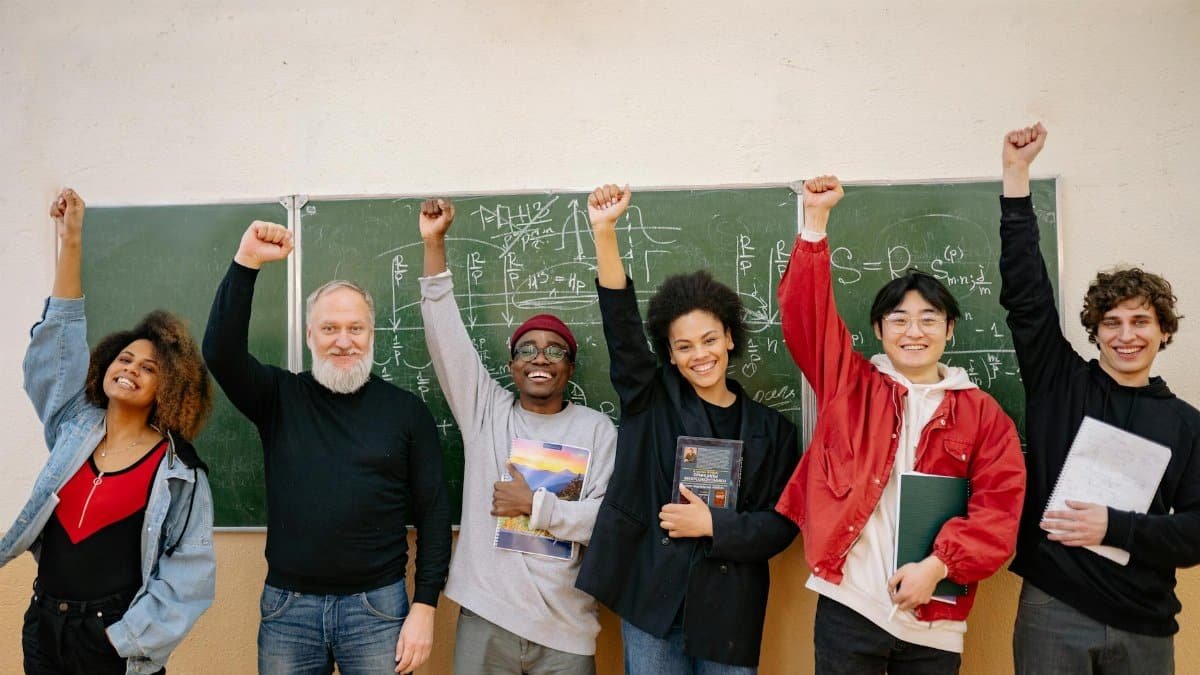 A cheerful group of diverse students and a teacher celebrating in front of a chalkboard full of equations.