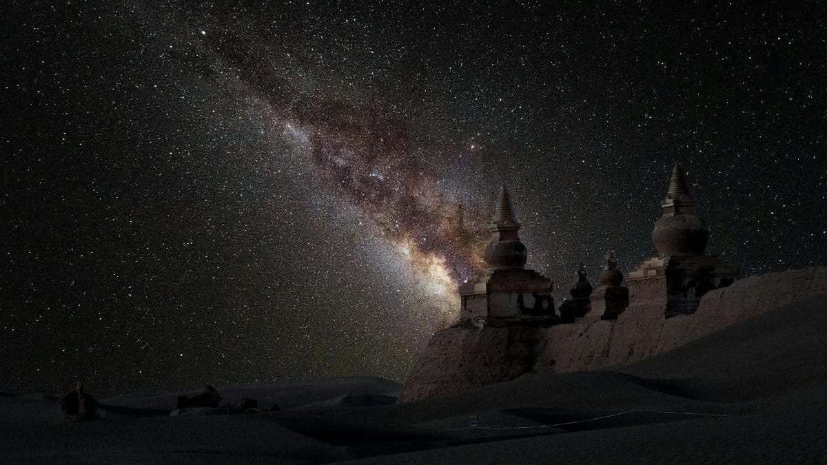 Spectacular scenery of frozen snowy historic architecture on vast winter valley beneath dark night sky with numerous bright glowing stars