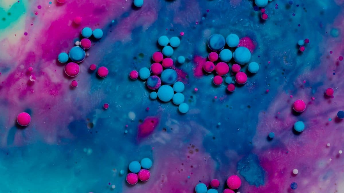 A close-up of colorful pink and blue bubbles in liquid, creating an artistic and abstract pattern.