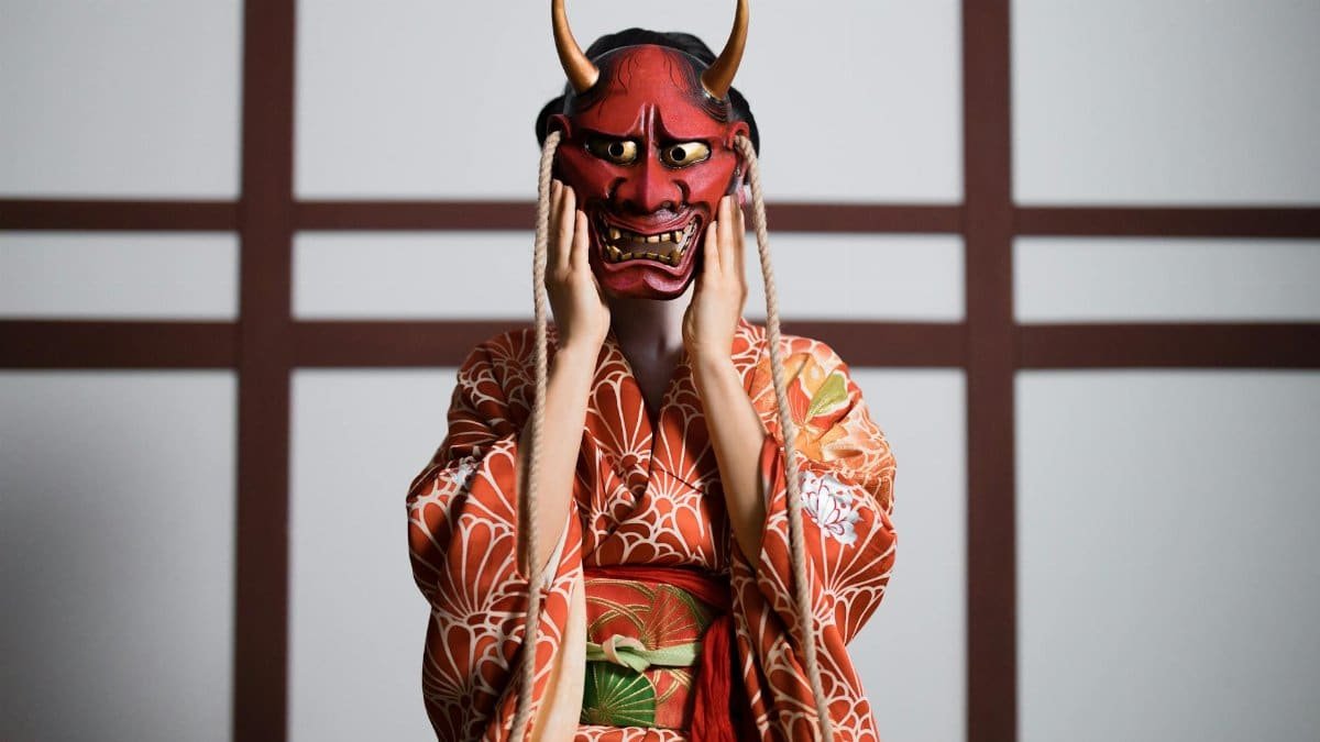 Person in a traditional Japanese kimono wearing a red Hannya mask with horns.