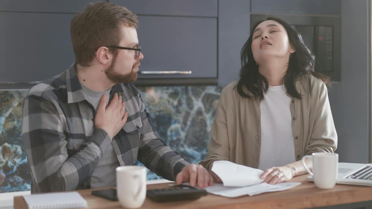 A couple experiencing stress while discussing finances in a modern kitchen setting.