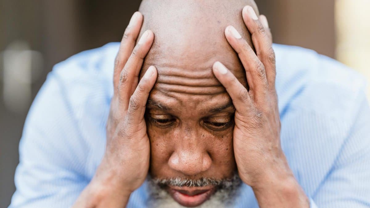 A worried bald man holds his head, depicting stress and concern.