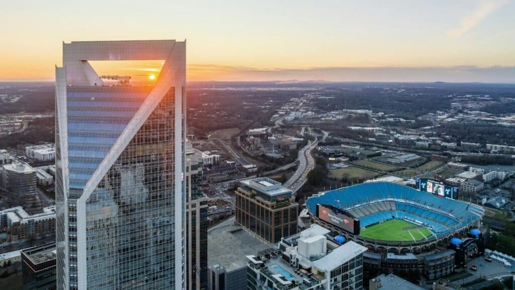 Aerial view of Charlotte's skyline and Bank of America Stadium during vibrant sunset.