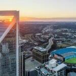 Aerial view of Charlotte's skyline and Bank of America Stadium during vibrant sunset.