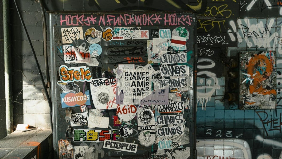 A vibrant wall covered with diverse stickers and graffiti in an urban setting.