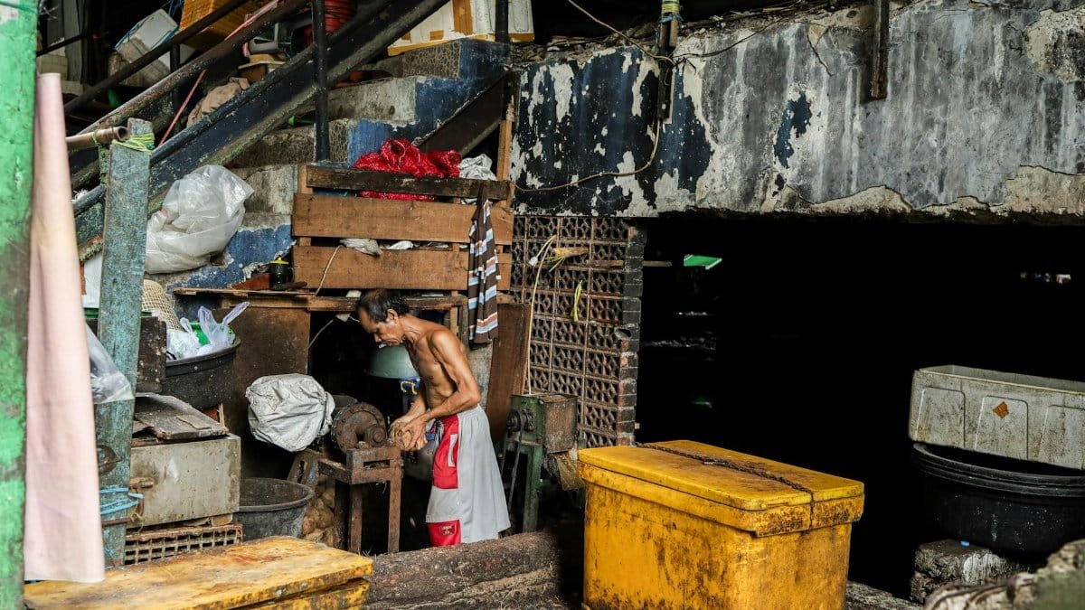 A man working surrounded by clutter in a gritty urban alleyway, conveying industrial life.